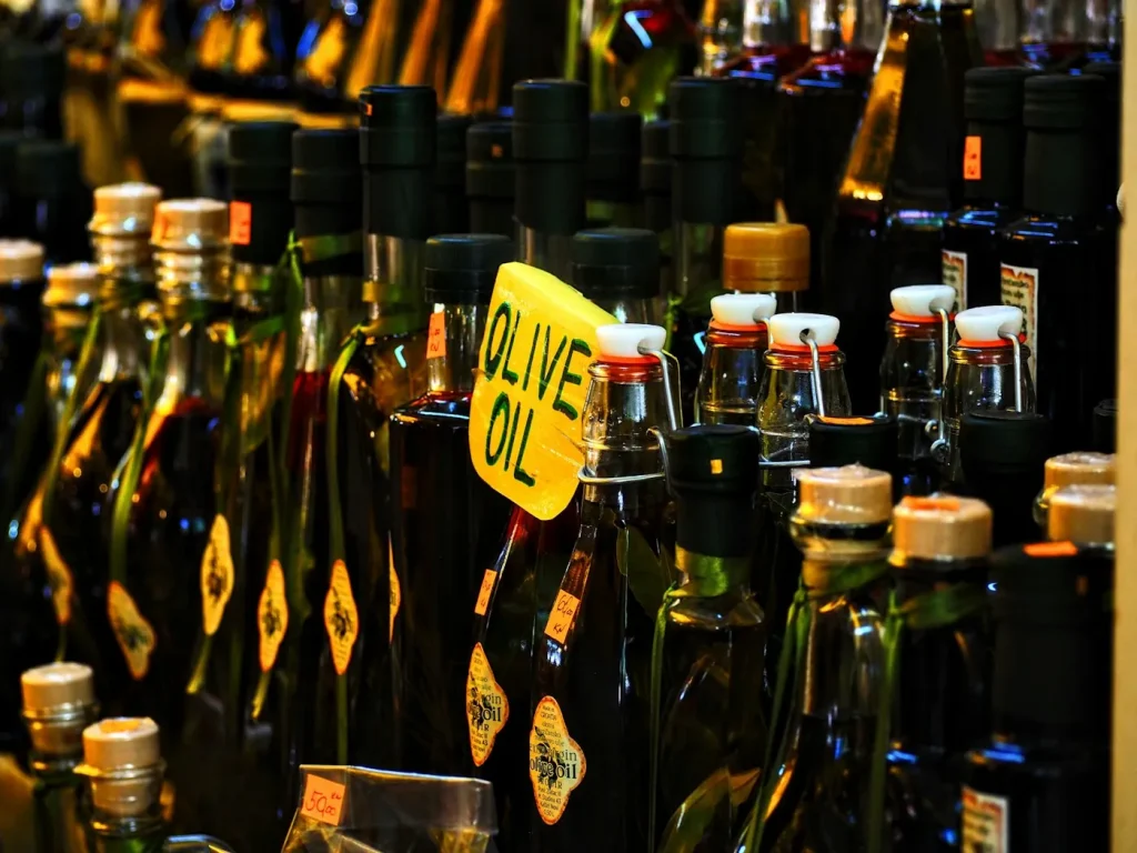 Bottle of extra virgin olive oil next to fresh olives
