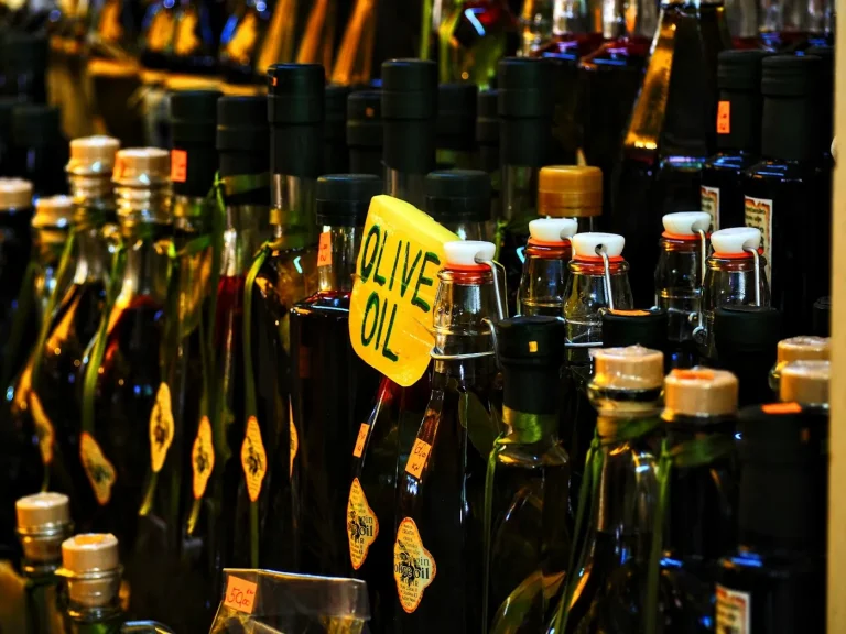 Bottle of extra virgin olive oil next to fresh olives