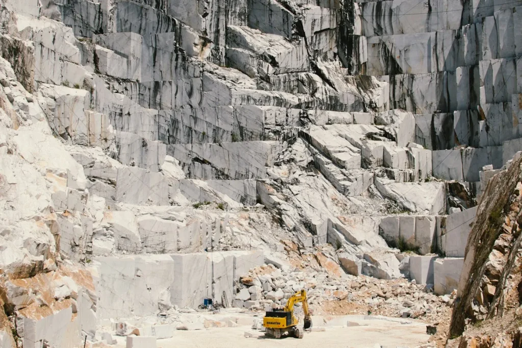 Loader moving a large stone block in a quarry yard